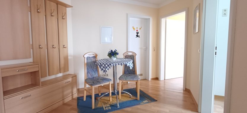 Diele Heller Flur mit Tisch und Stühlen, Holzschränken und heller Wandgestaltung.