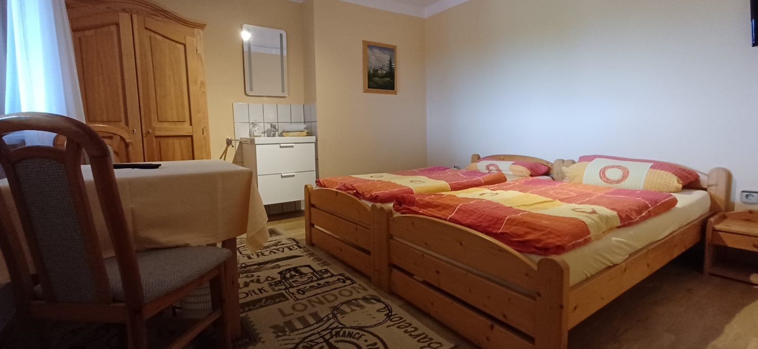 Doppelzimmer Gemütliches Zimmer mit zwei Betten, Tisch und Holzschränken. Helle, einladende Atmosphäre.