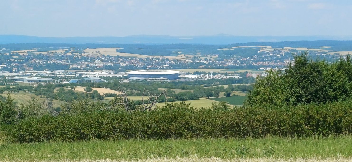 Stadion Weite Landschaft mit sanften Hügeln und einem Blick auf die Stadt im Hintergrund.